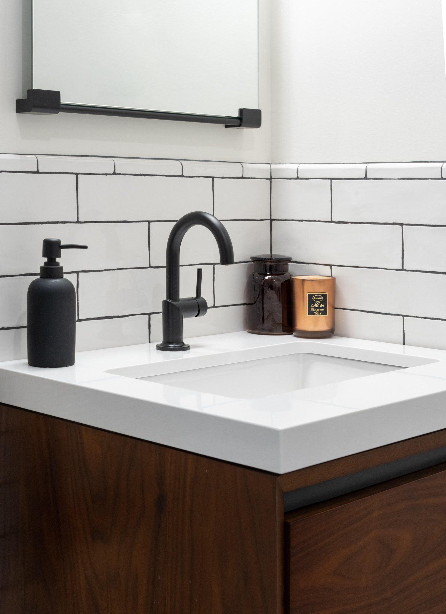 White subway tile bathroom with black faucet, rectangular mirror, and clean modern finishes