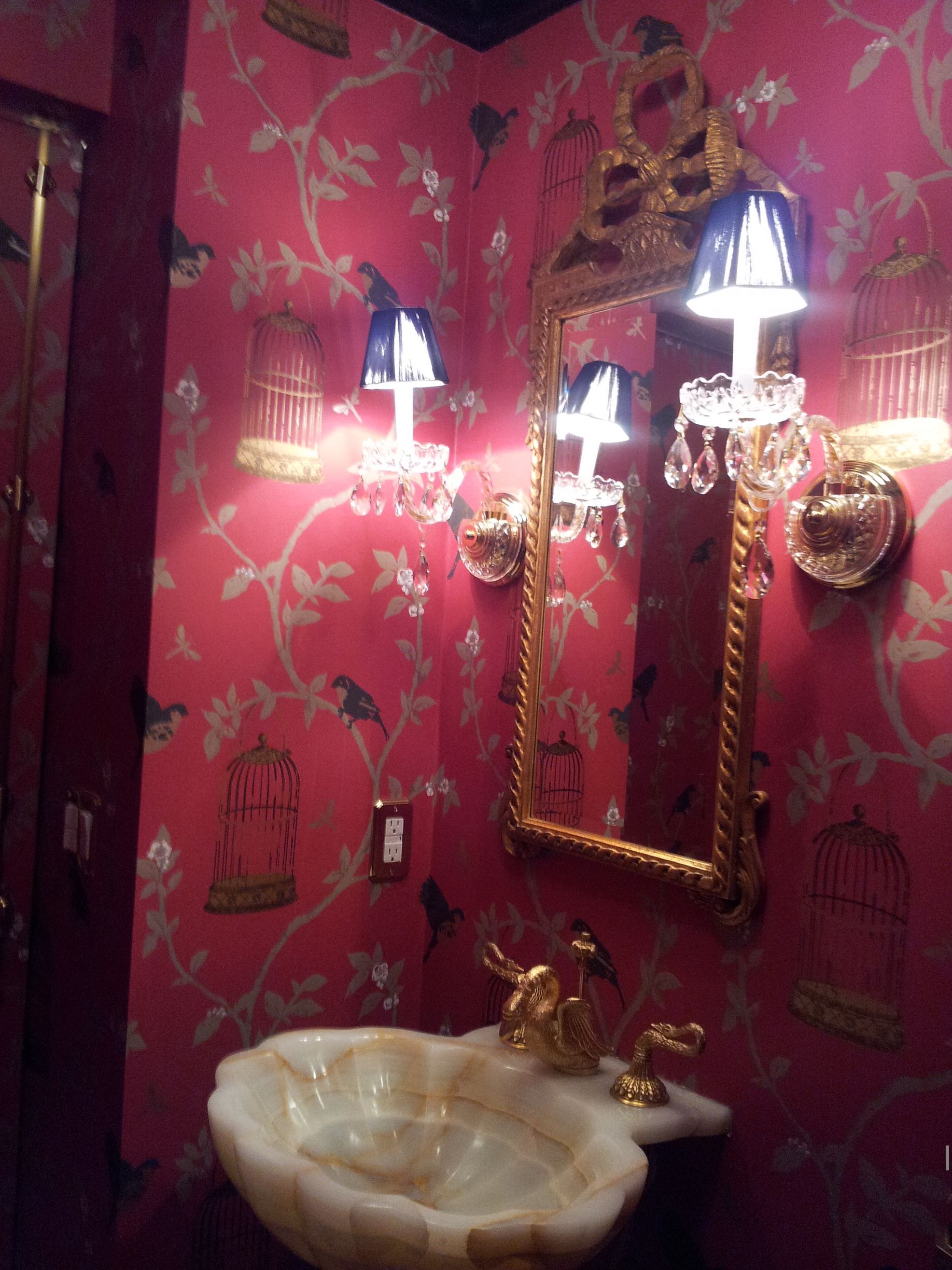 Red wallpaper bathroom with ornate mirror, wall sconces, and decorative lighting