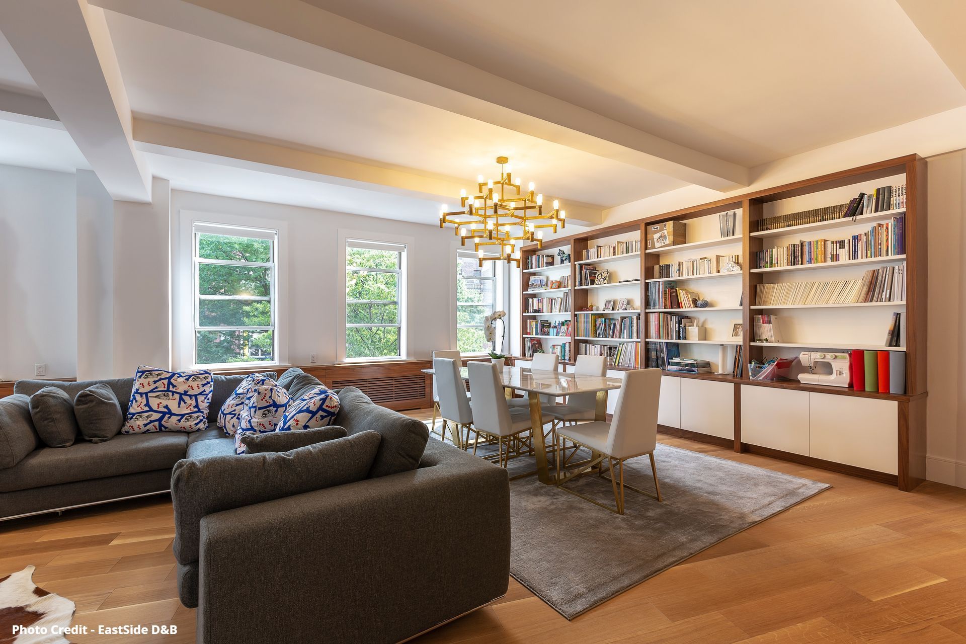 Living room with built-in bookshelves, sofa, chandelier, and large windows