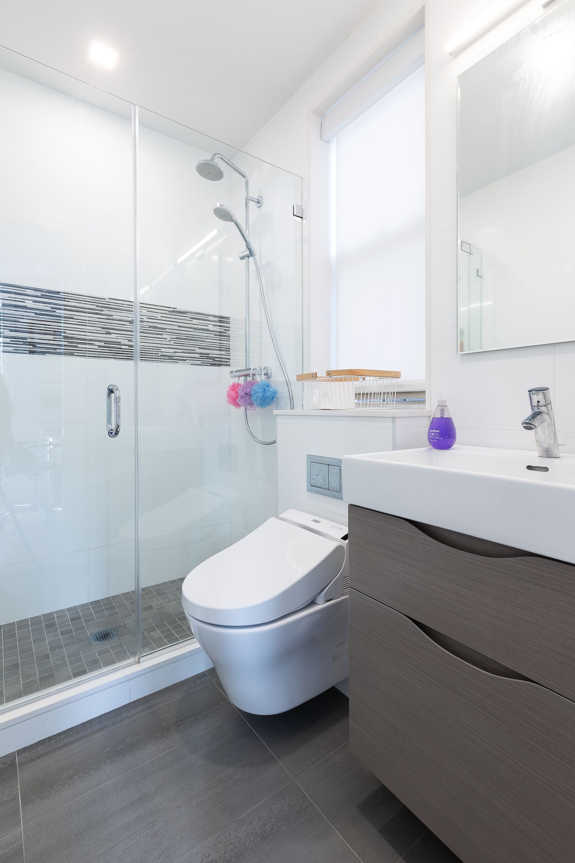 Bright white bathroom shower with glass enclosure, window, and modern shower fixture