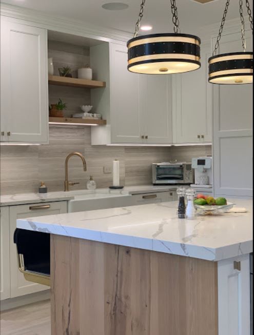 White kitchen cabinets with open shelving, wood backsplash detail, and black pendant lights