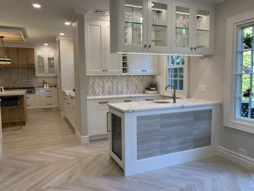 Bright kitchen with glass-front cabinets, island sink, tile backsplash, and open layout