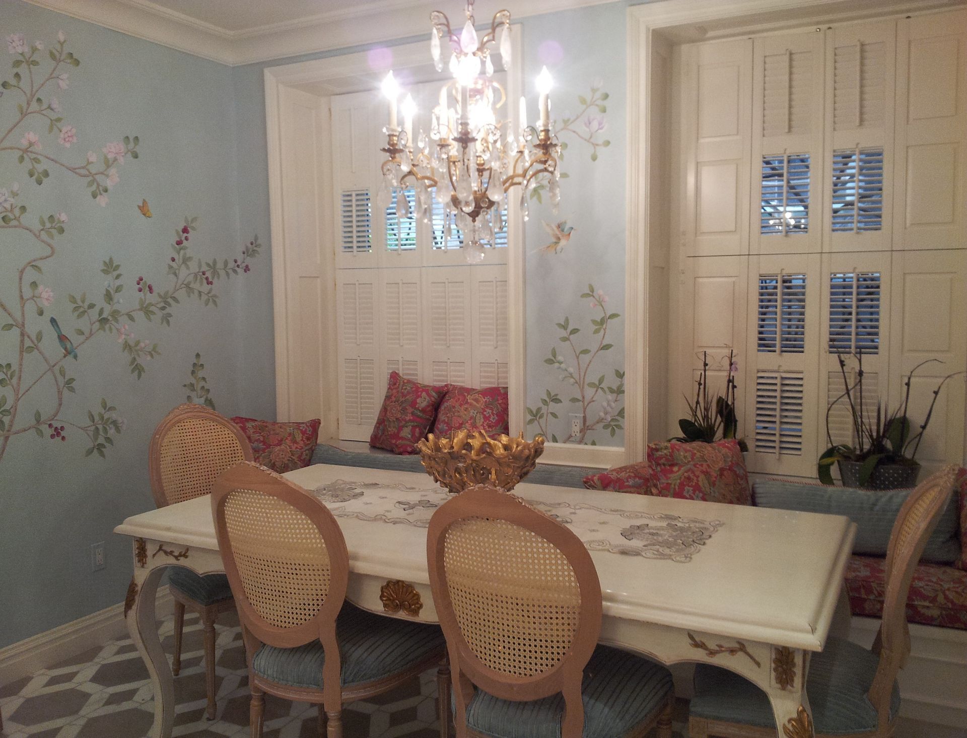 Dining nook with floral wallpaper, chandelier, upholstered bench, and table seating