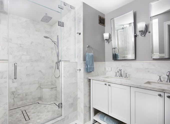 Carrara marble bathroom with glass shower, double vanity, mirror, and chrome fixtures
