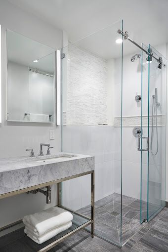 Glass shower enclosure with white tile, chrome fixtures, and modern bathroom lighting