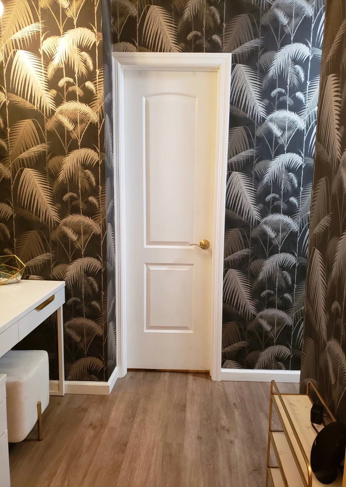 Hallway with White interior door framed by dark tropical wallpaper