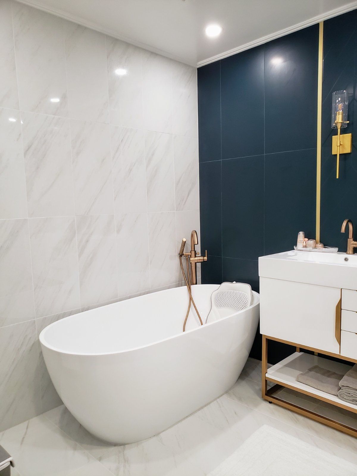 White and emerald green bathroom shower wall with brass shower fixture and marble-look tile