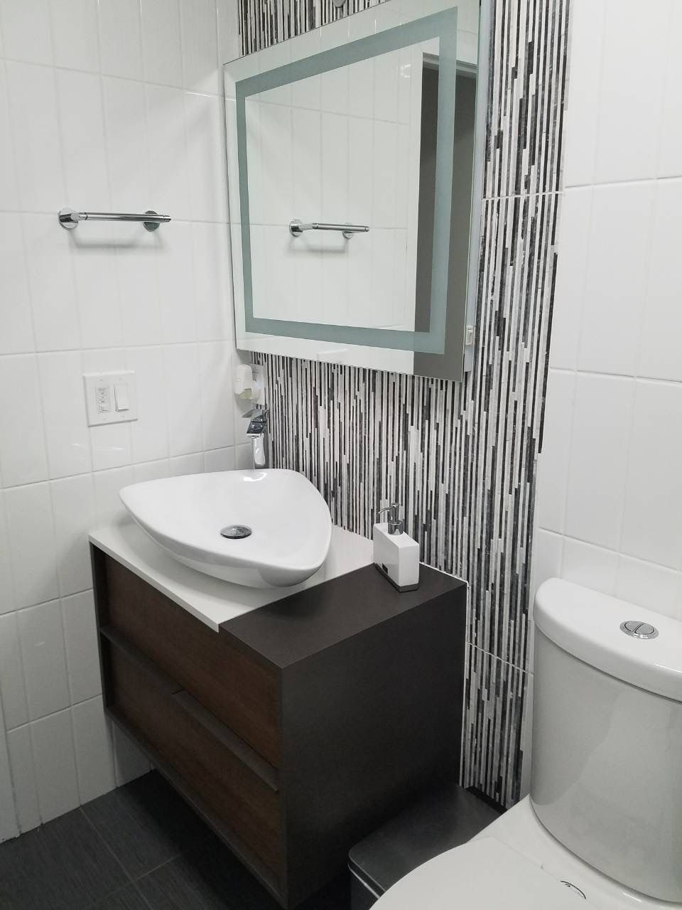 Bathroom vanity wall with framed mirror, towel bar, and vertical mosaic tile accent