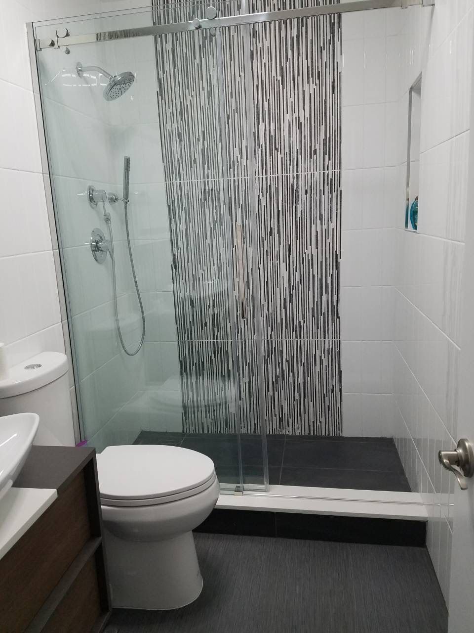 Glass shower with vertical mosaic tile accent, chrome fixtures, and white wall tile