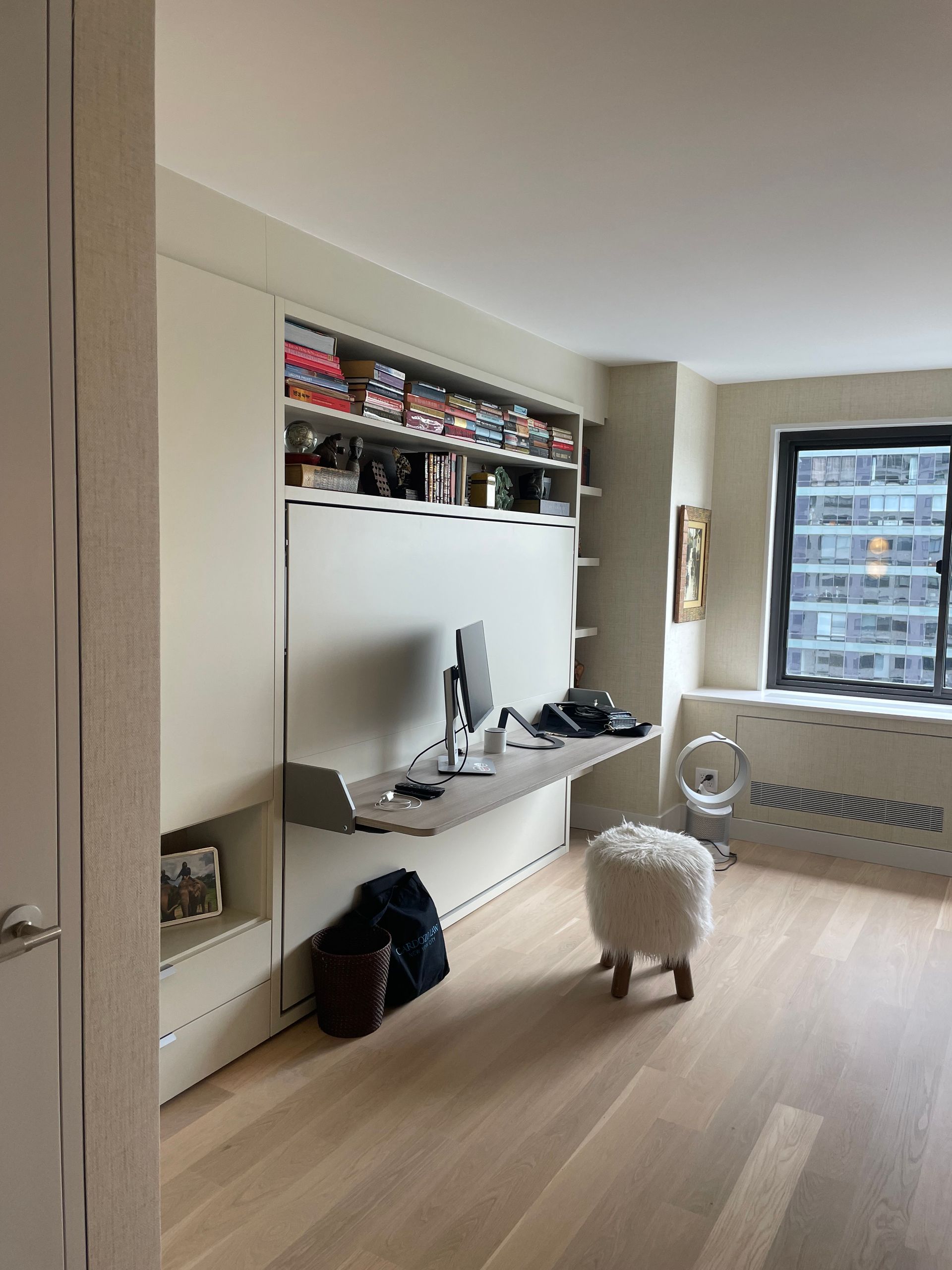 Built-in shelving with books and storage beside a bright window