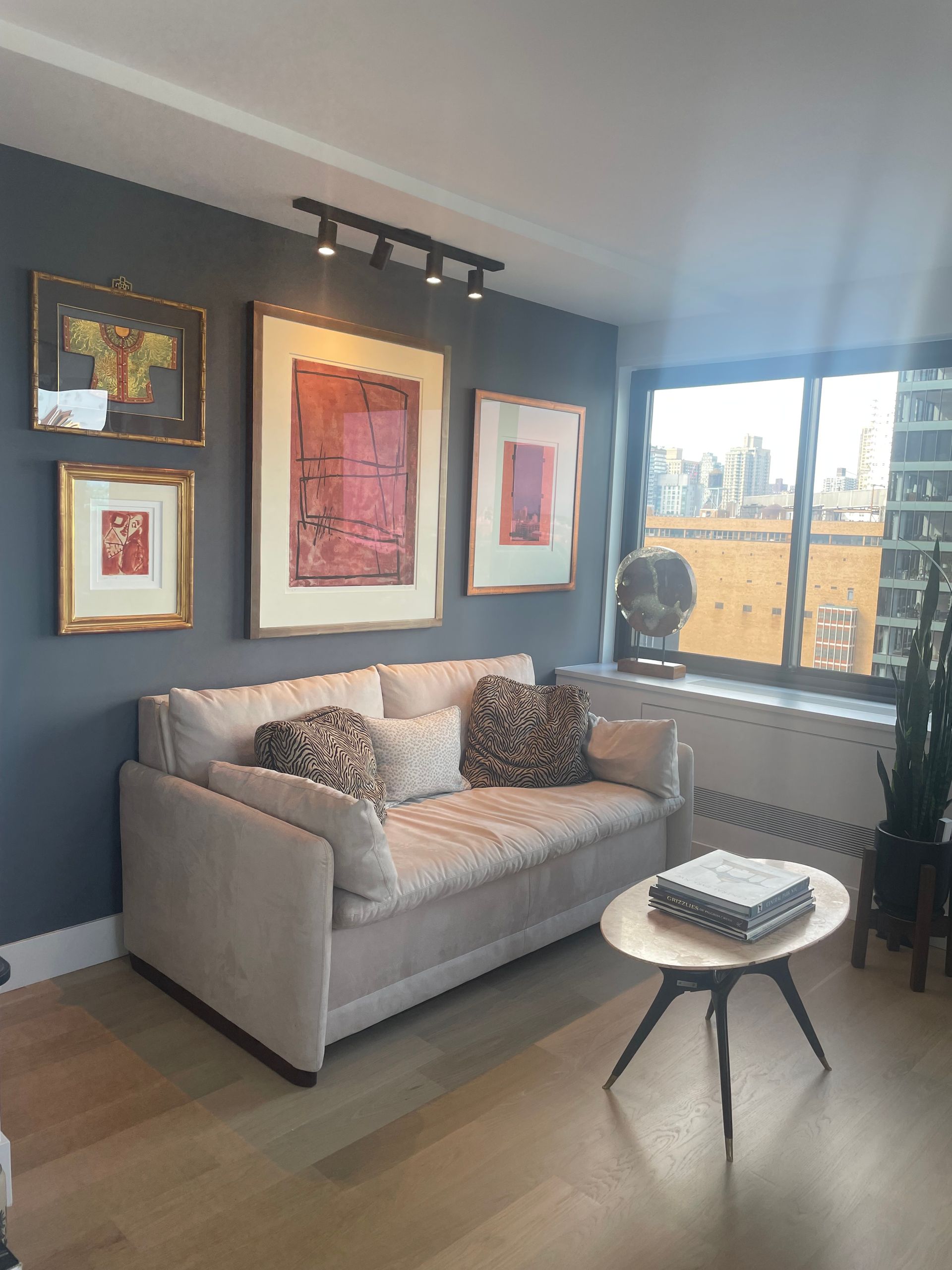 Interior wall with framed artwork, track lighting, and city view from the window
