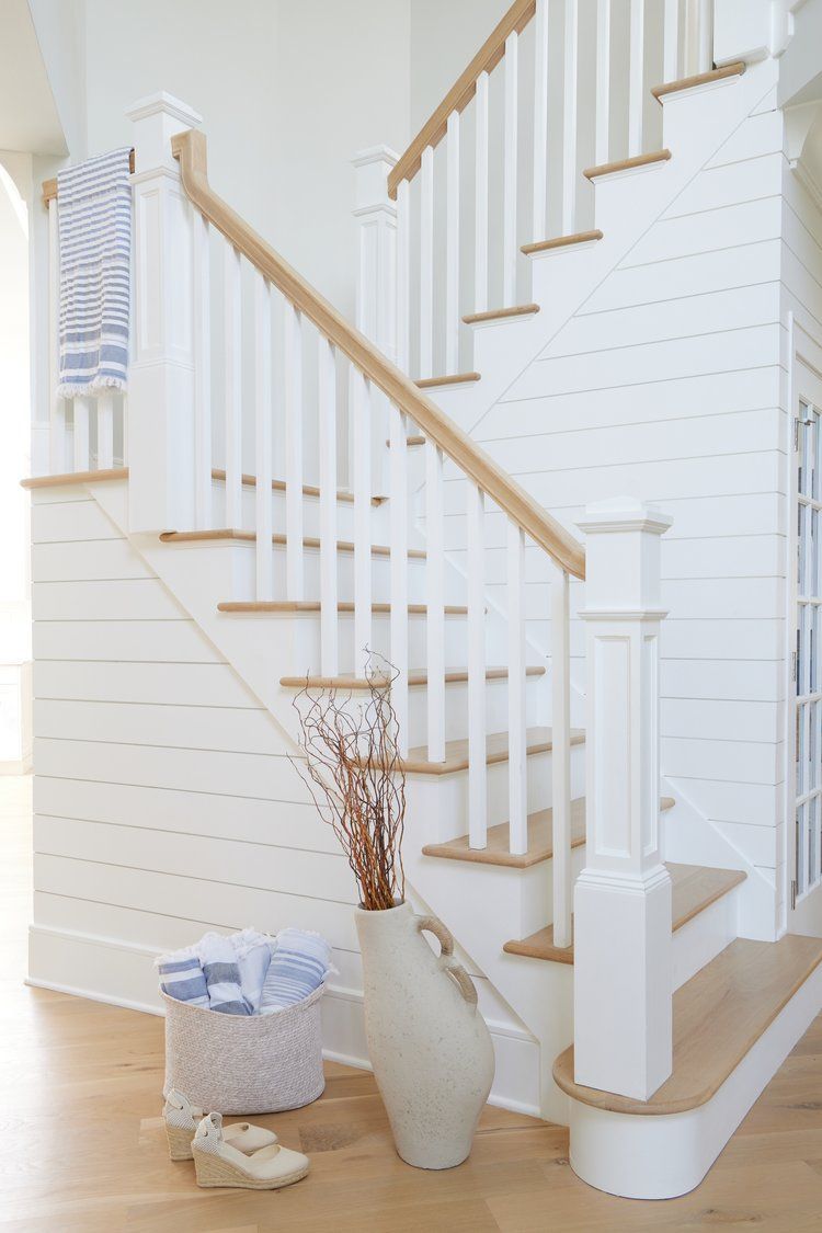 Foyer with White staircase with wood handrail, shiplap wall, and blue striped towel accent