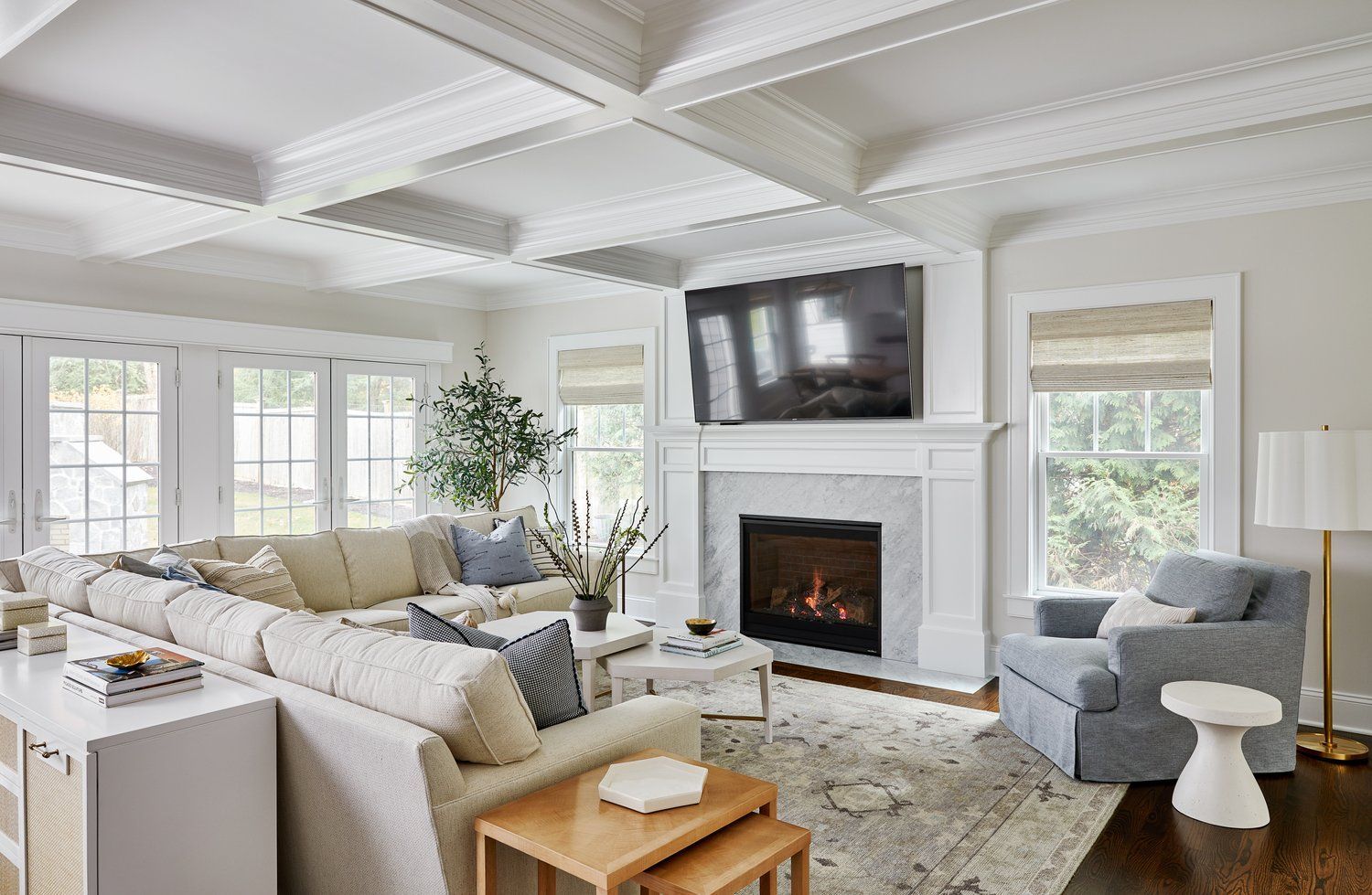 Bright family room with coffered ceiling, fireplace, sectional sofa, and large windows