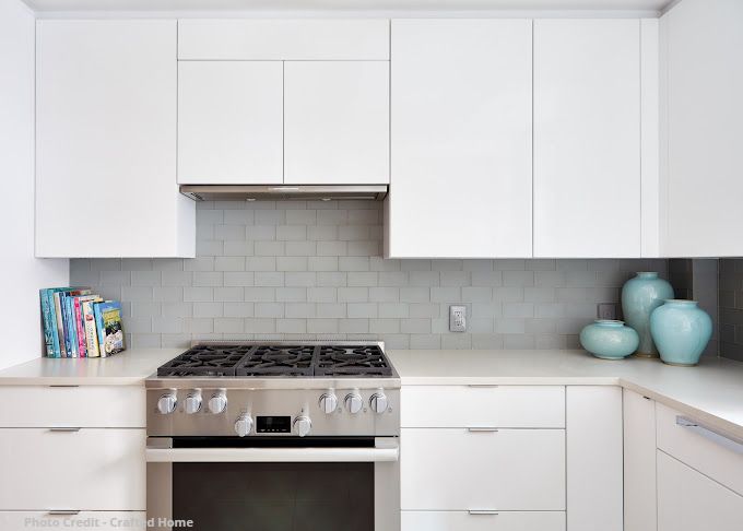 White kitchen range wall with gas stove, subway tile backsplash, and simple modern cabinetry