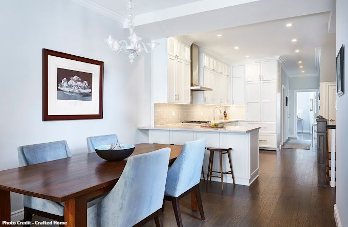 Open dining and kitchen area with wood table, blue chairs, white cabinets, and island seating