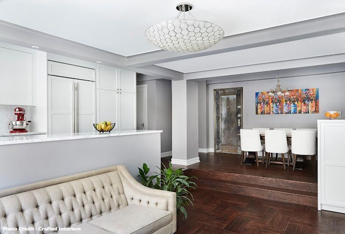 Elegant open living and dining room with chandelier, white cabinetry, and upholstered seating