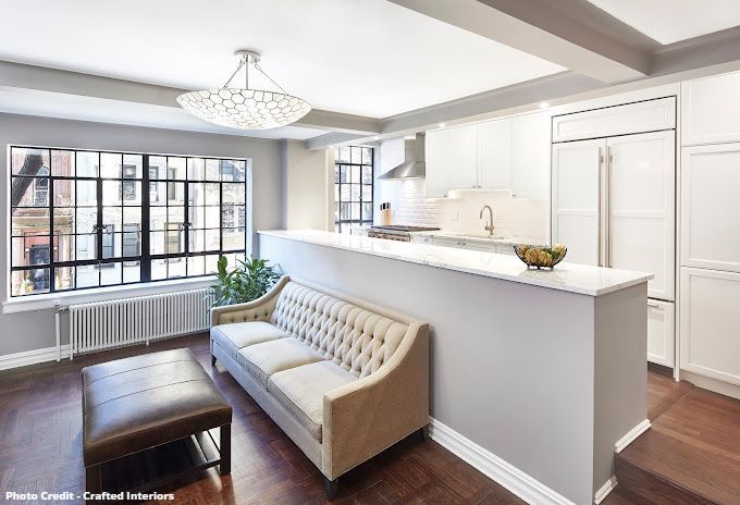 Bright open kitchen and living area with white cabinetry, island seating, and city window view