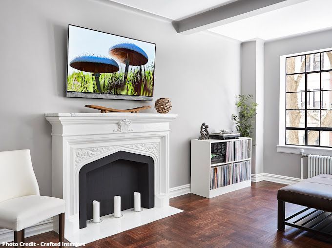 Living room with white fireplace, mounted TV, city window view, and modern décor