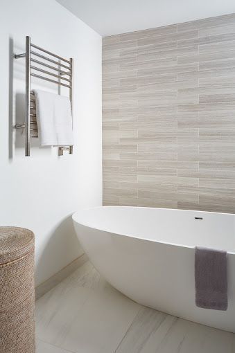 Bright bathroom with freestanding tub, wall mounted towel warmer and neutral tile
