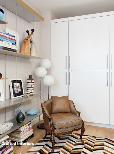 White built-in office  with shelving, books, and decorative accessories, with a larg closet divider 