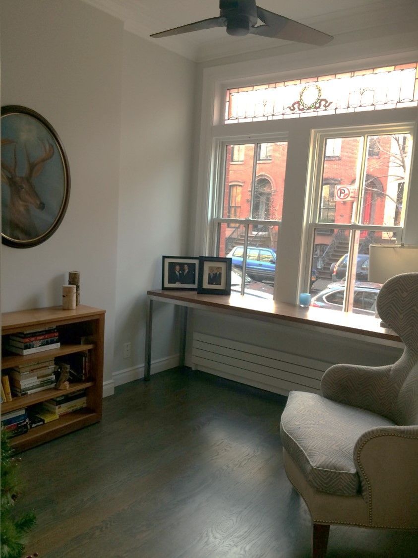 Home office Bright room corner with ceiling fan, tall window, round wall art, and city view