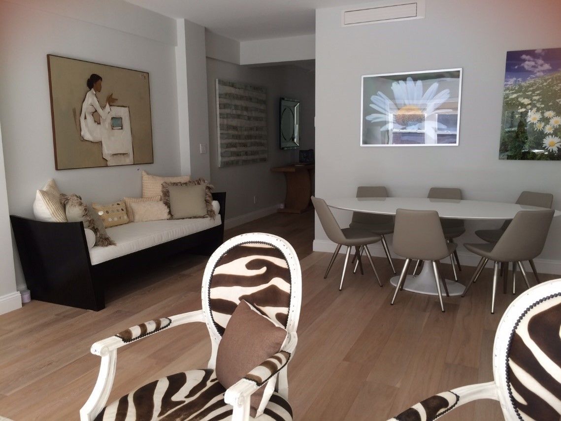 Open living and dining area with wall art, sofa, dining table, and modern chairs