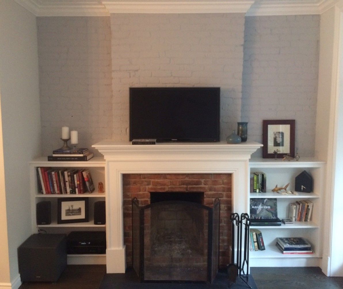 Living room with white fireplace, built-in shelves, wall-mounted TV, and soft neutral décor