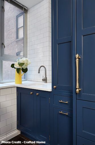 Kitchen window beside blue cabinetry and white subway tile backsplash