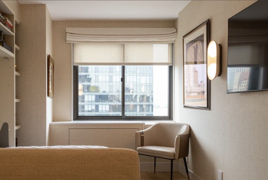 Cozy bedroom sitting area with window, armchair, built-in shelves, and framed artwork