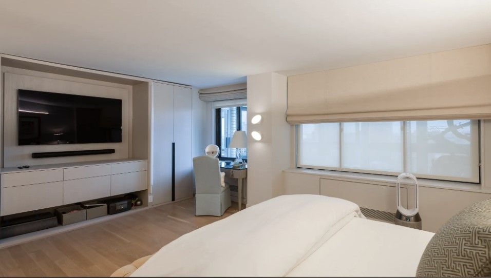 Modern bedroom with built-in wall unit, bed, window shade, and soft neutral finishes