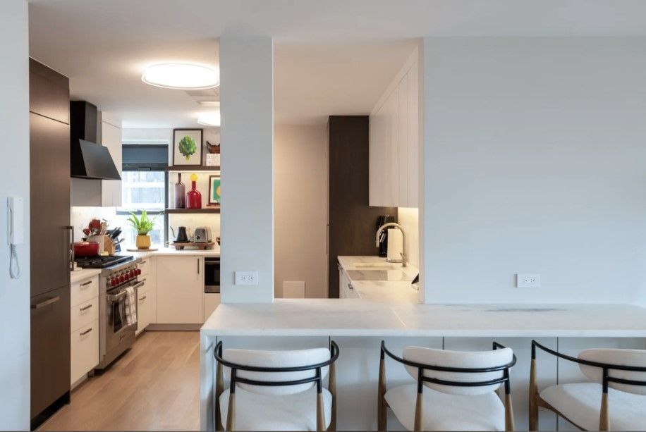 Modern kitchen with white island, bar stools, black cabinetry, and open shelving
