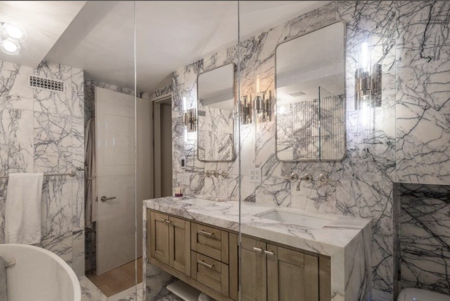 Lilah Marble bathroom vanity with large mirror, wall sconces, and polished stone finishes