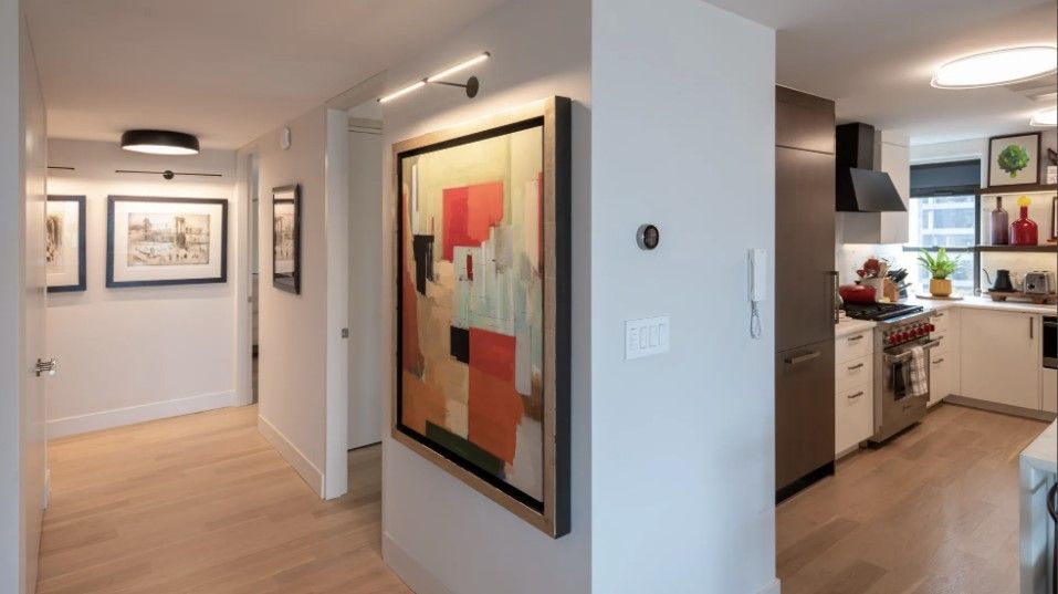 Modern hallway with large wall art leading into a kitchen and living area