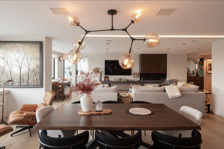 Open living and dining room with modern chandelier, neutral furniture, and warm lighting
