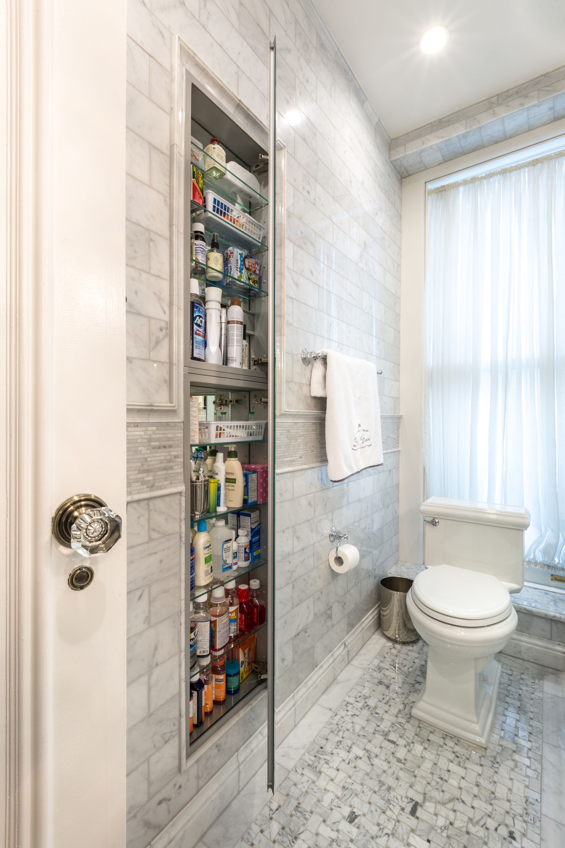 Marble bathroom shower area with built-in shelving, window, and soft natural light