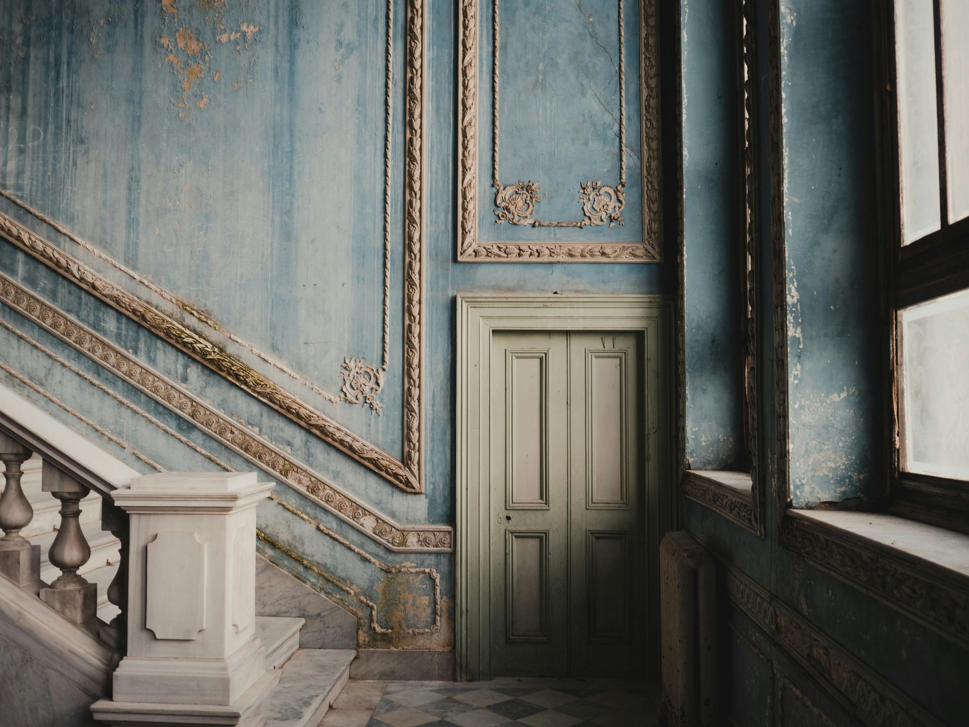 Historic interior wall with blue painted panels, decorative molding, and window light