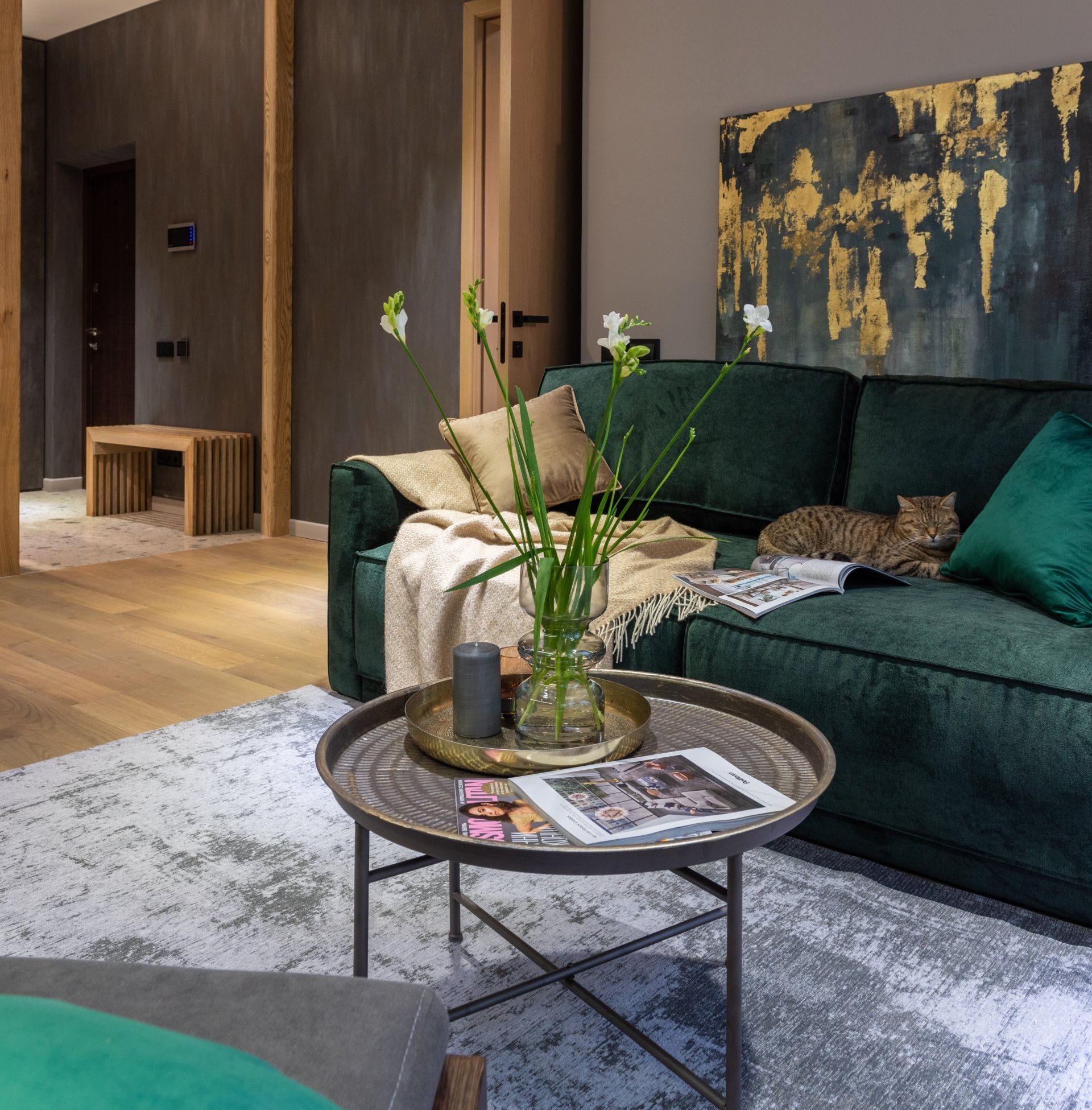 Stylish Living room with green velvet seating, dark artwork, wood paneling, and plants