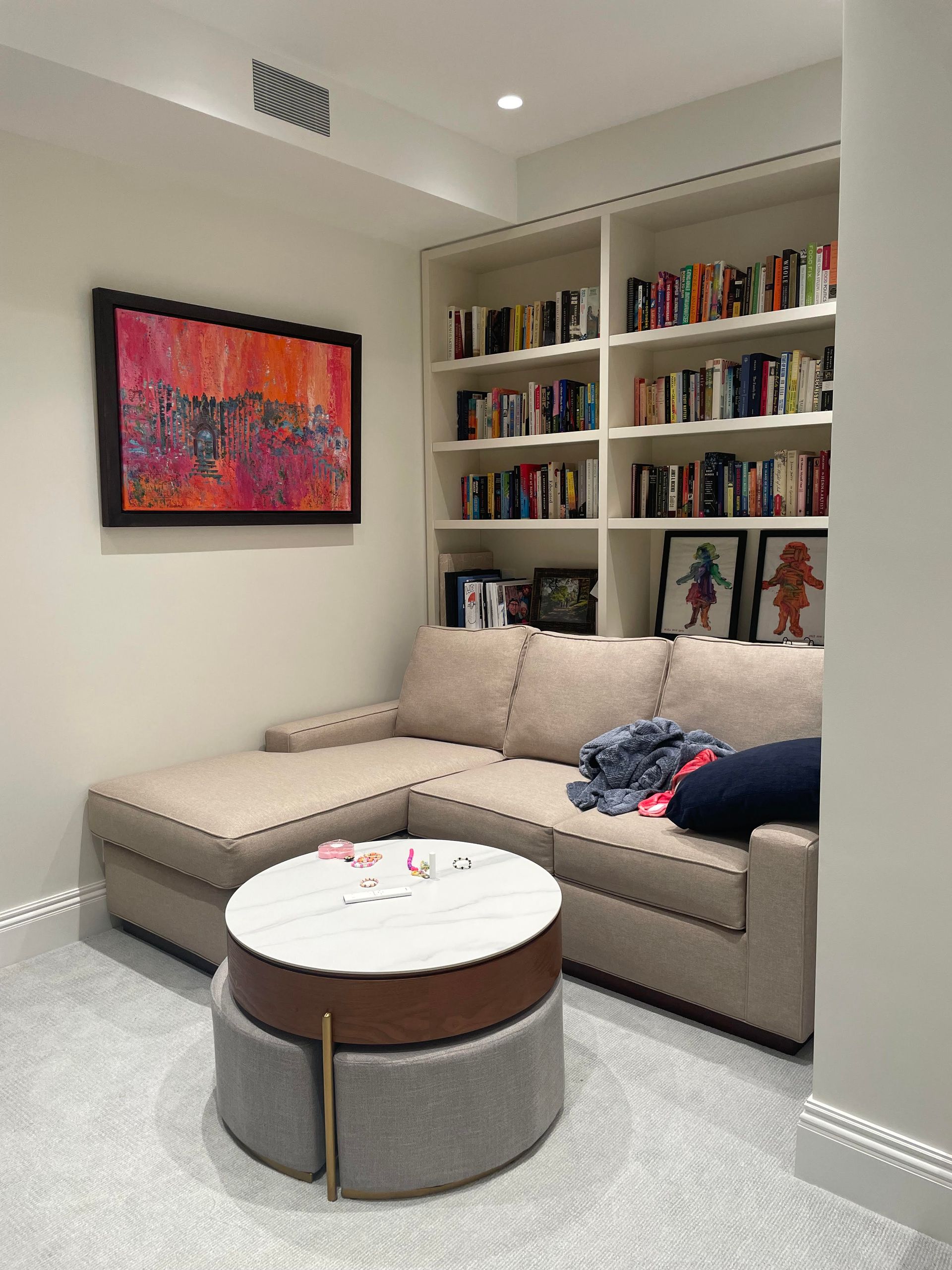 Built-in bookshelf with colorful books and red abstract artwork in a modern room, Reading Nook