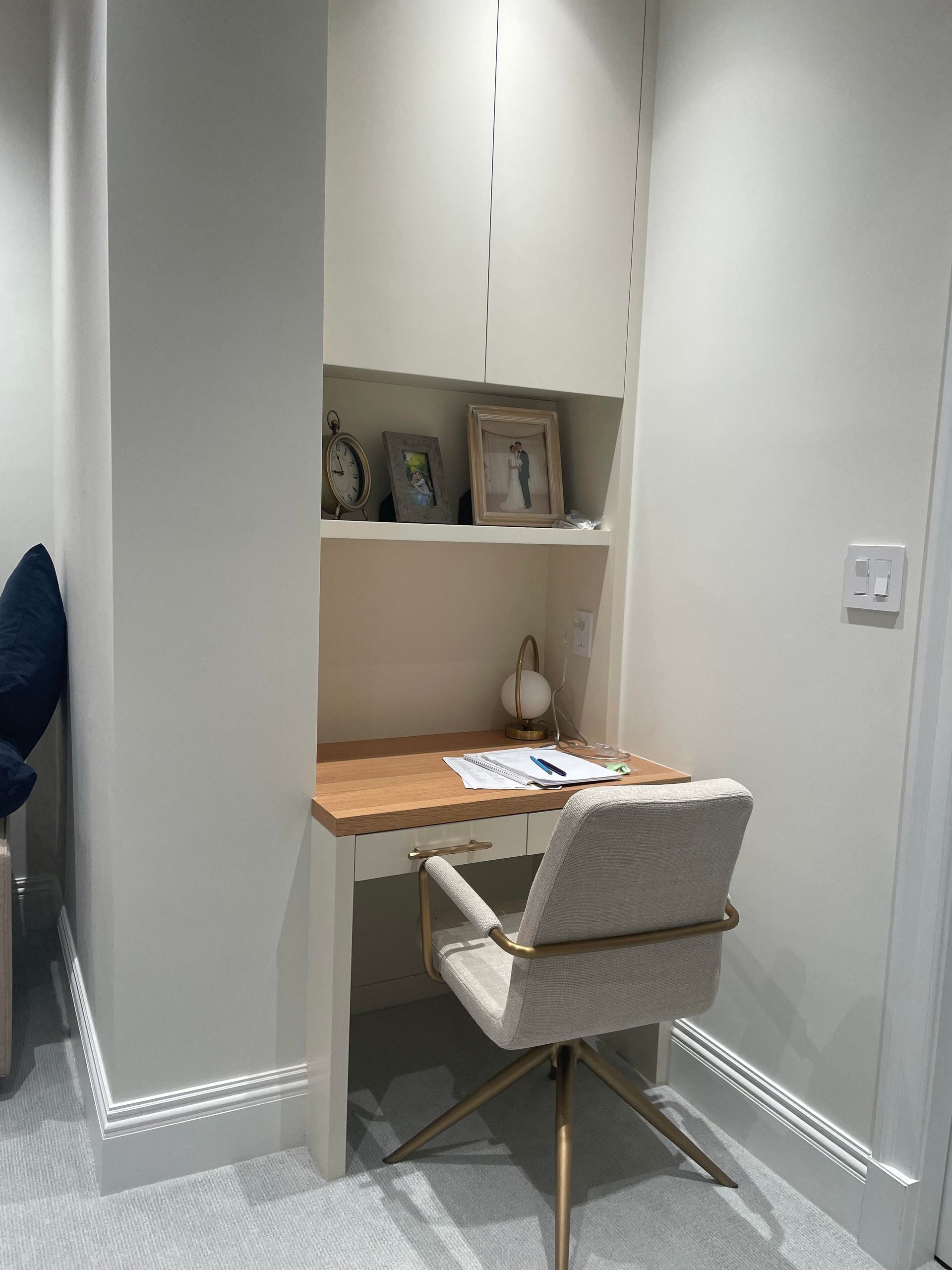 Minimal wall niche with framed photos and soft hallway lighting, used for small working desk space