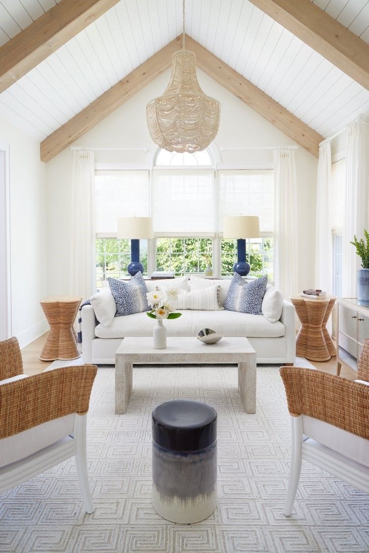 Living Room with Vaulted white ceiling with exposed wood beams, woven chandelier, and tall windows and coastal style furniture 