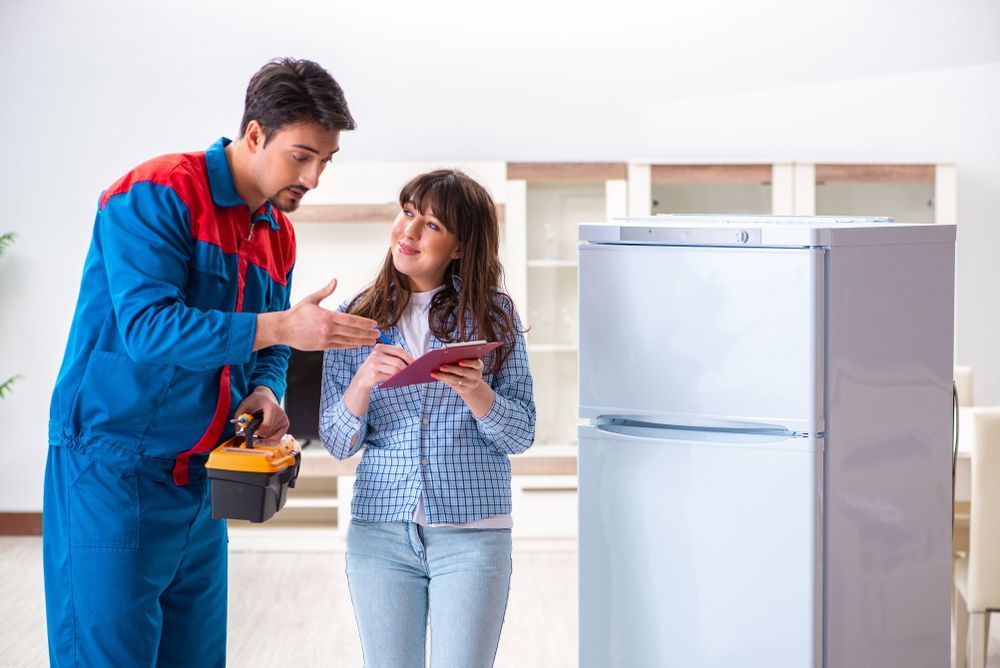 A Man and Women Holding Clipboard Discussing About Refrigerator In A Living Room — Appliance City in Port Macquarie, NSW