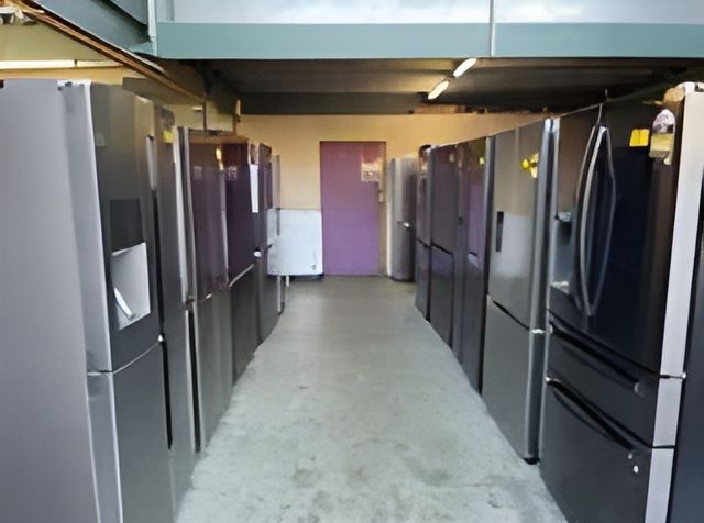A Man In Blue Overalls Is Opening A Refrigerator Door In A Kitchen — Appliance City in Port Macquarie, NSW