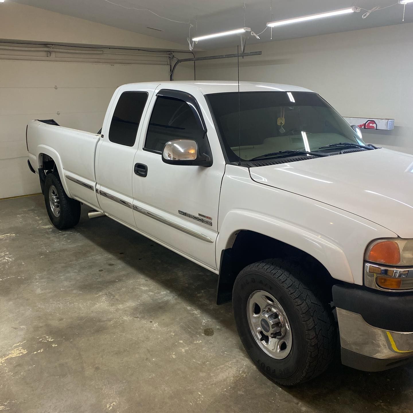 White Chevrolet Silverado pickup truck parked in a garage. The truck has tinted windows and chrome accents.