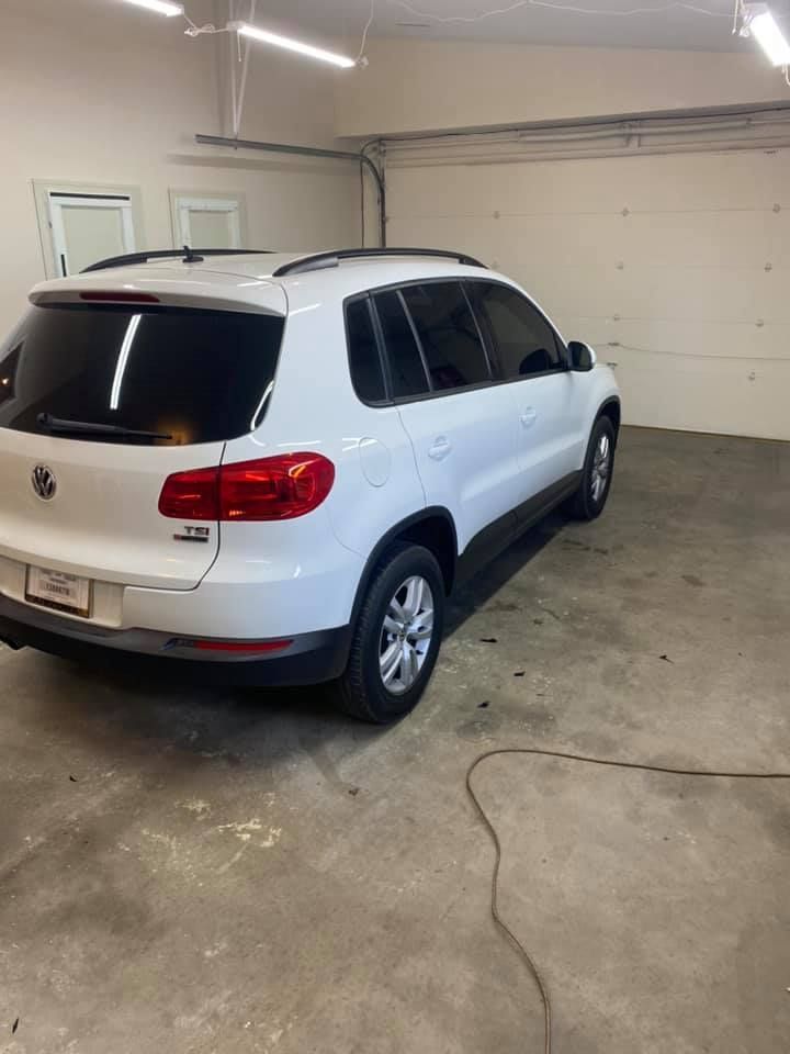 White Volkswagen Tiguan SUV parked inside a garage. The car has tinted windows and is angled towards the viewer.