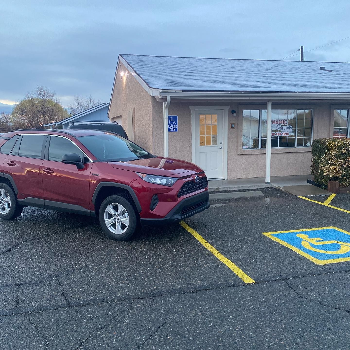 A red Toyota RAV4 parked in front of a building with a handicap parking spot marked in blue.
