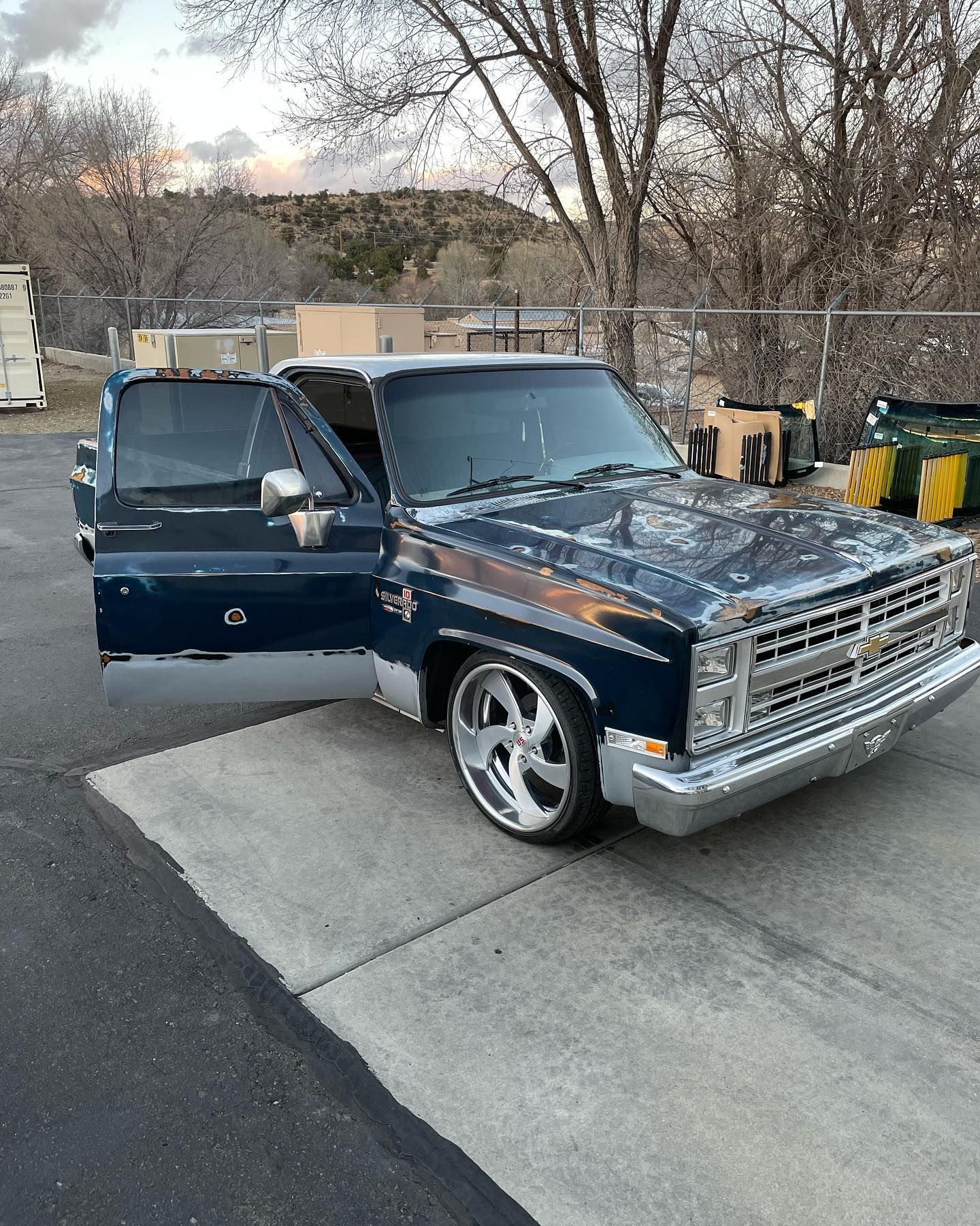 Dark blue classic Chevrolet pickup truck with chrome wheels, parked outdoors with the door open.