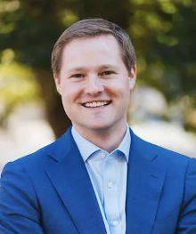 A man in a blue suit and white shirt is smiling for the camera.