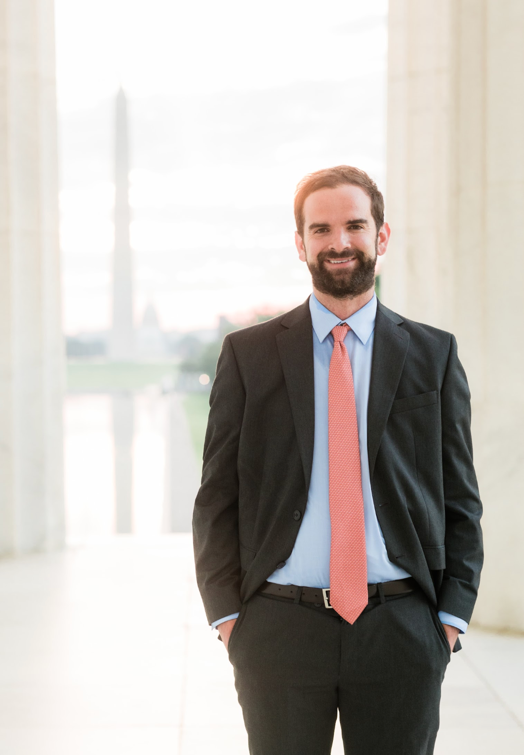 A man in a suit and tie is standing with his hands in his pockets.