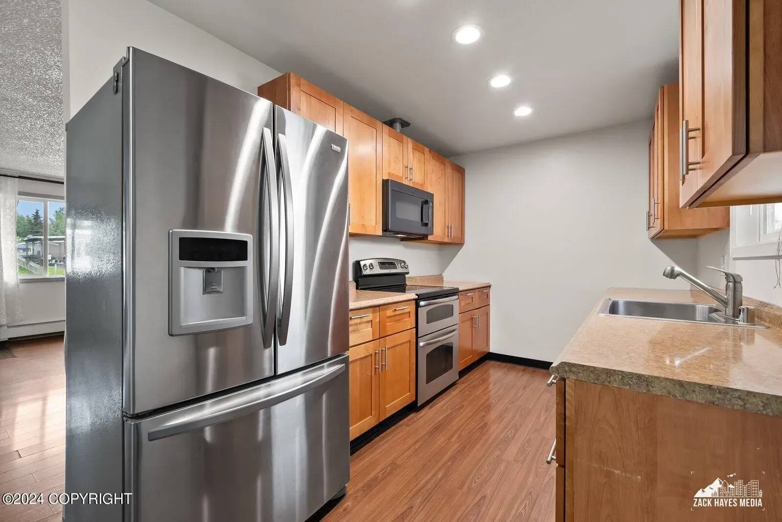 Kitchen with stainless steel appliances, light wood cabinets, and granite countertops.