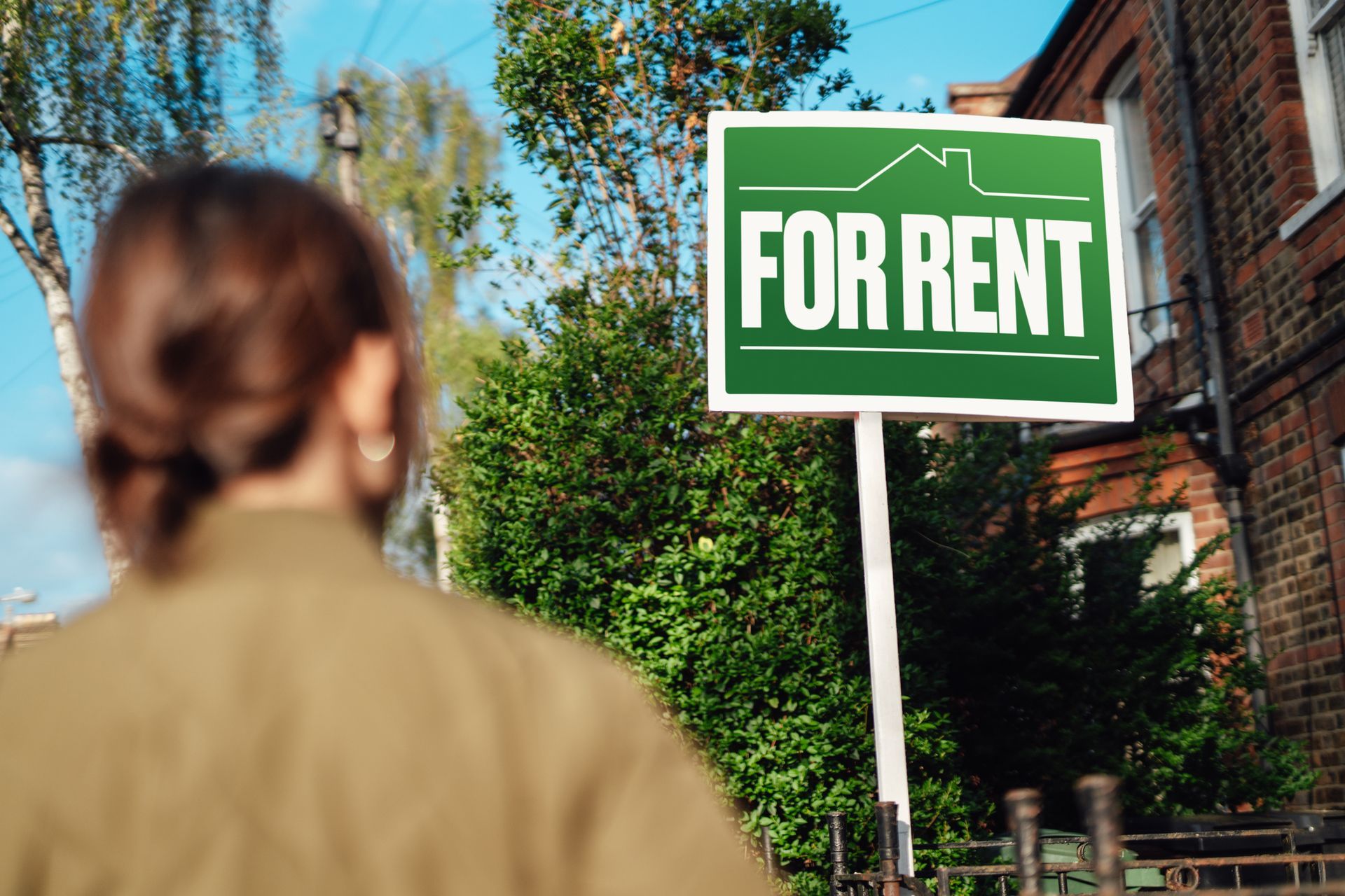 Woman looking at real estate sign planning to rent a house.